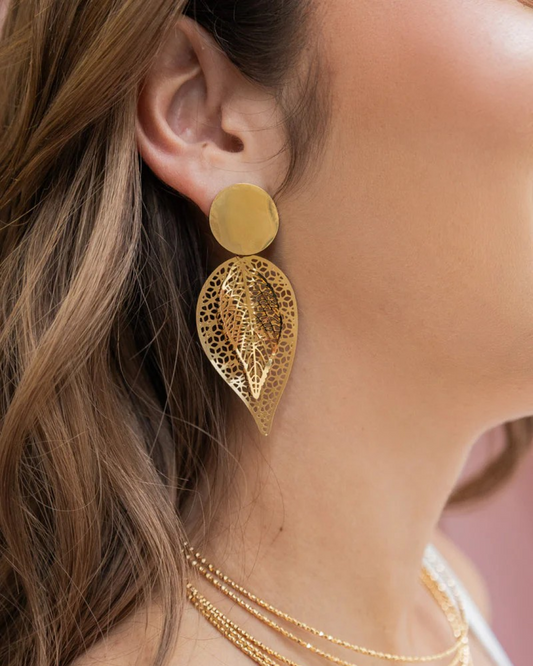Gold double-leaf filigree drop earring with round stud base worn on a woman’s ear in profile.