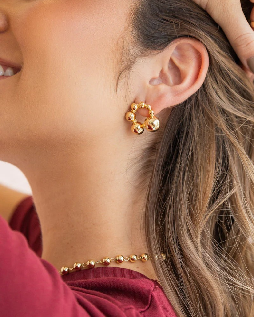 Gold bubble stud forming a small hoop on the model’s ear.