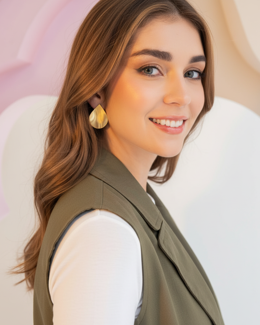 Model wearing satin-finish golden teardrop earrings against a soft background.