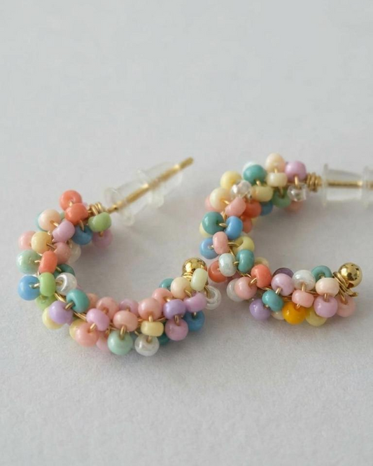 Pair of pastel beaded mini hoop earrings with a gold-tone base on a neutral background.