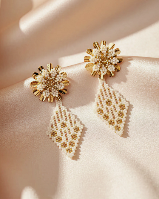 Ivory-and-gold Miyuki flower & diamond drop earrings on satin fabric.