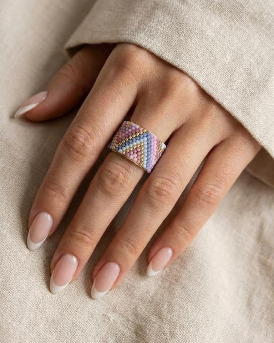 Macro detail of an adjustable Miyuki-woven ring with pastel beads and gold lines.