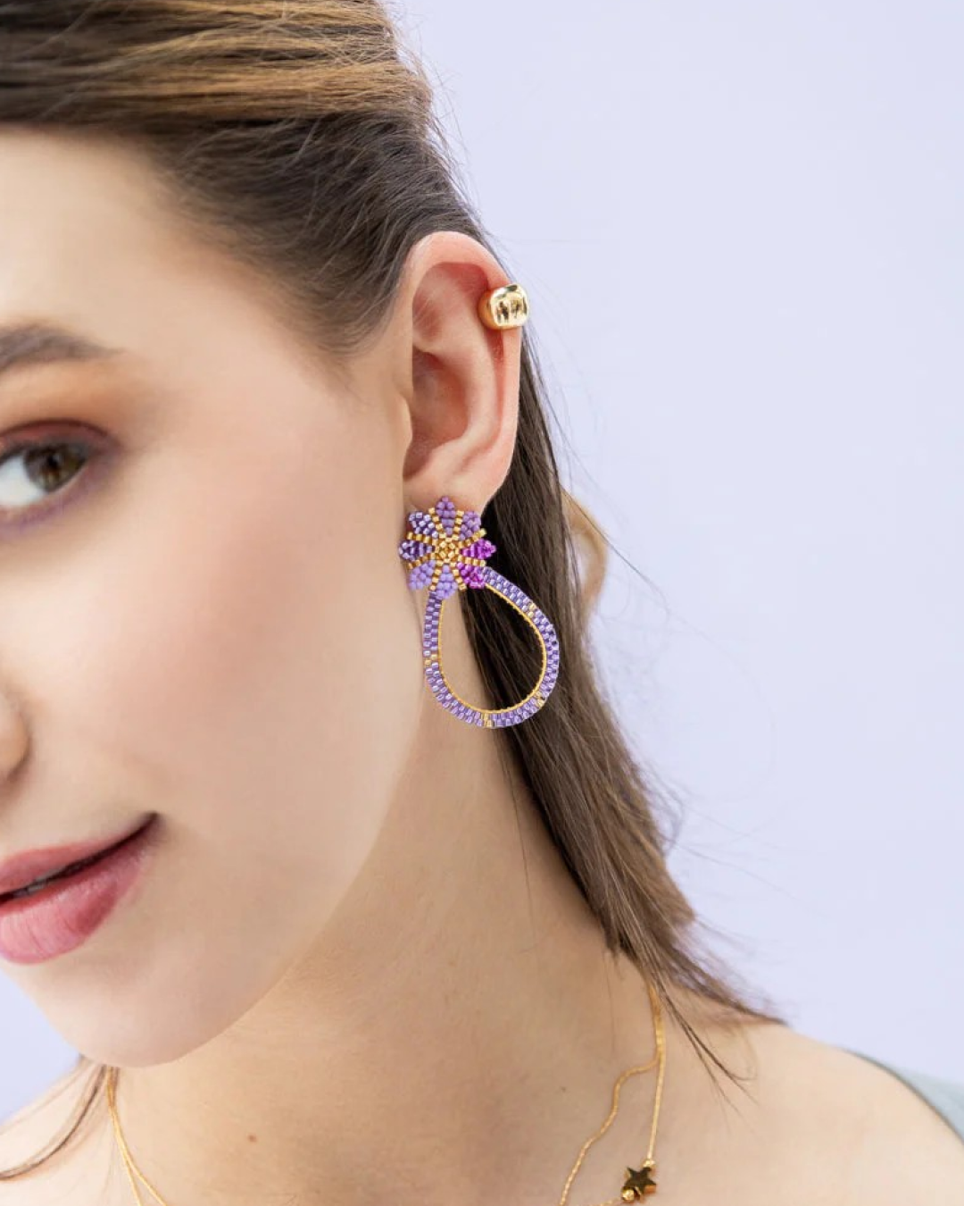 Lilac Miyuki beaded flower and teardrop earrings with 24k gold-plated brass on model, beige background.