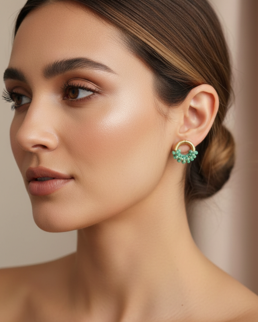 Close-up of model wearing gold stud earrings with a mint bead cluster.