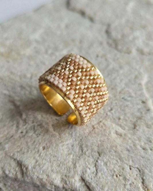 Adjustable nude and gold Miyuki ring displayed on a stone surface.