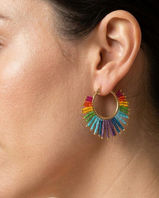 Woman wearing a gold hoop earring with multicolor Miyuki fringe.