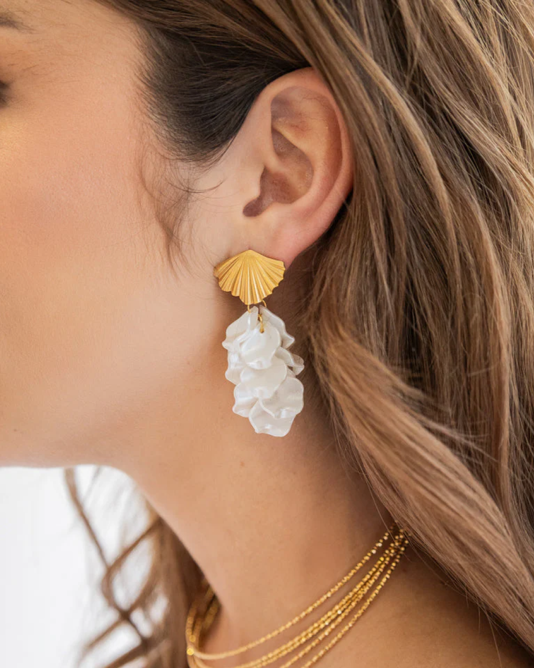 Model wearing ‘Seafoam Shell Drops’: gold shell stud and ivory mother-of-pearl-style drop.